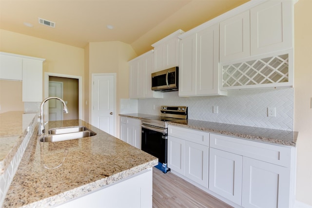 kitchen with white cabinetry, stainless steel appliances, backsplash, light stone countertops, and sink