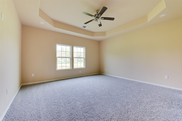 unfurnished room featuring ceiling fan, carpet flooring, and a raised ceiling