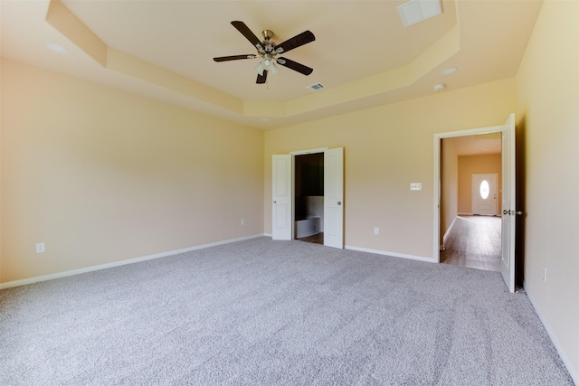 unfurnished bedroom featuring light carpet, ceiling fan, and a raised ceiling