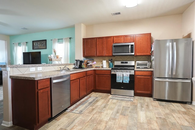 kitchen featuring kitchen peninsula, backsplash, sink, and stainless steel appliances