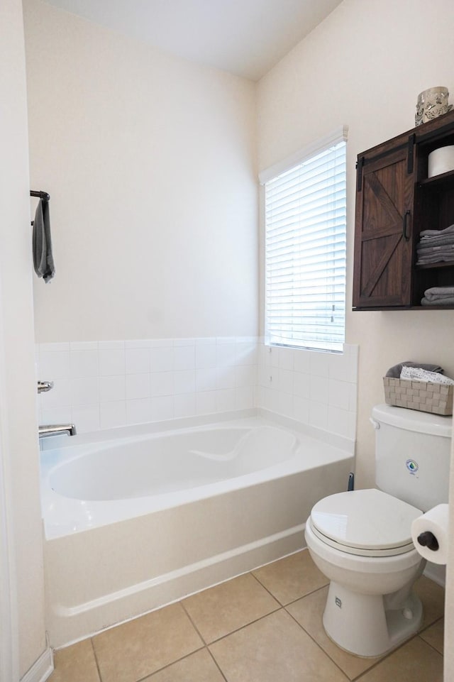 bathroom with tile patterned floors, toilet, and a tub to relax in