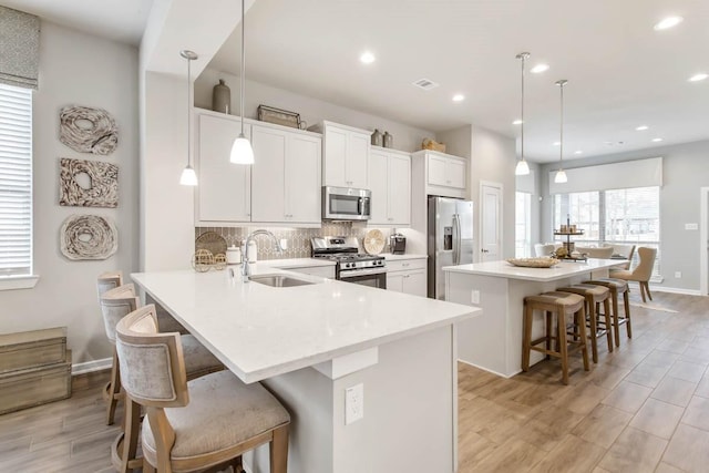 kitchen with pendant lighting, stainless steel appliances, sink, a kitchen breakfast bar, and kitchen peninsula