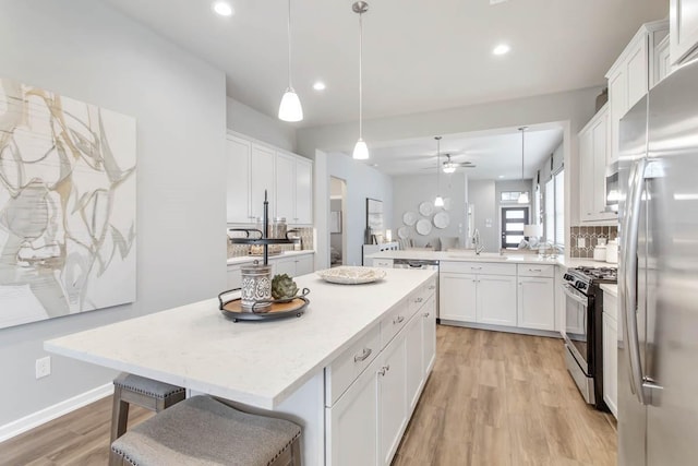 kitchen with a kitchen island, decorative light fixtures, white cabinetry, stainless steel appliances, and a kitchen breakfast bar