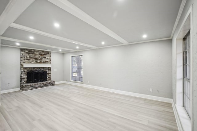 unfurnished living room featuring crown molding, light hardwood / wood-style floors, a fireplace, and beamed ceiling