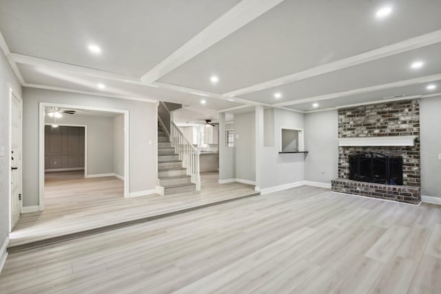 unfurnished living room featuring ceiling fan, light wood-type flooring, a brick fireplace, and beamed ceiling