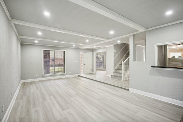 unfurnished living room featuring beam ceiling, ornamental molding, and light hardwood / wood-style flooring