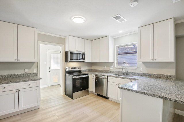 kitchen with light stone countertops, appliances with stainless steel finishes, white cabinets, and sink