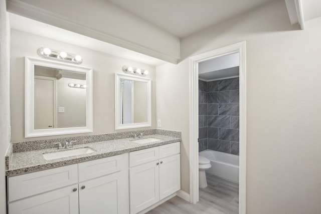 full bathroom with toilet, vanity, tiled shower / bath, and hardwood / wood-style floors