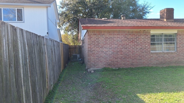 view of side of property with a yard and central AC unit