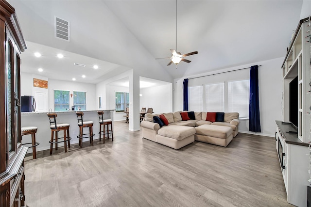 living room featuring light hardwood / wood-style floors, high vaulted ceiling, and ceiling fan