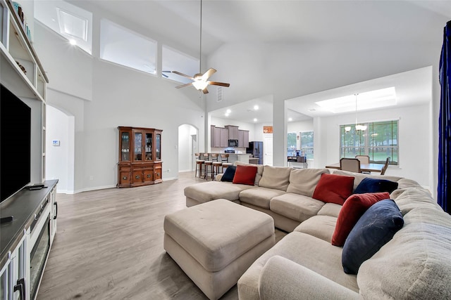 living room with ceiling fan, light hardwood / wood-style floors, and high vaulted ceiling