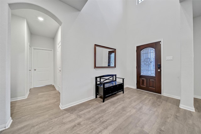 entryway with light hardwood / wood-style flooring and a towering ceiling