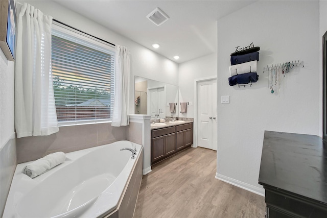 bathroom featuring tiled bath, wood-type flooring, and vanity