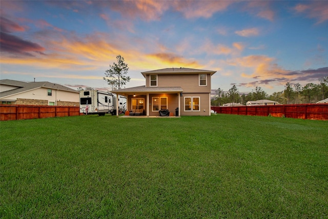 back house at dusk featuring a patio area and a yard