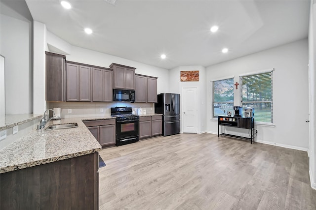 kitchen featuring light hardwood / wood-style floors, black appliances, sink, light stone countertops, and dark brown cabinets