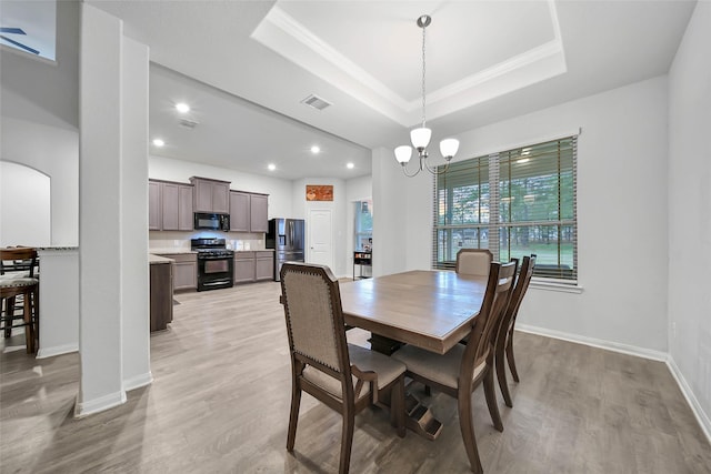 dining area featuring a chandelier, ornamental molding, light hardwood / wood-style flooring, and a tray ceiling