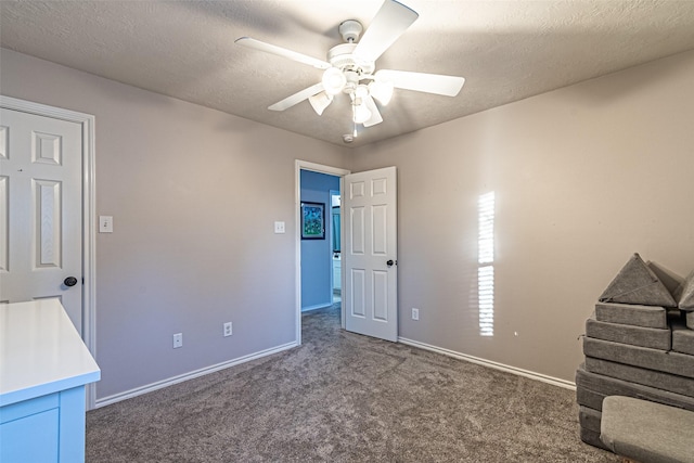 unfurnished bedroom featuring ceiling fan, dark carpet, and a textured ceiling