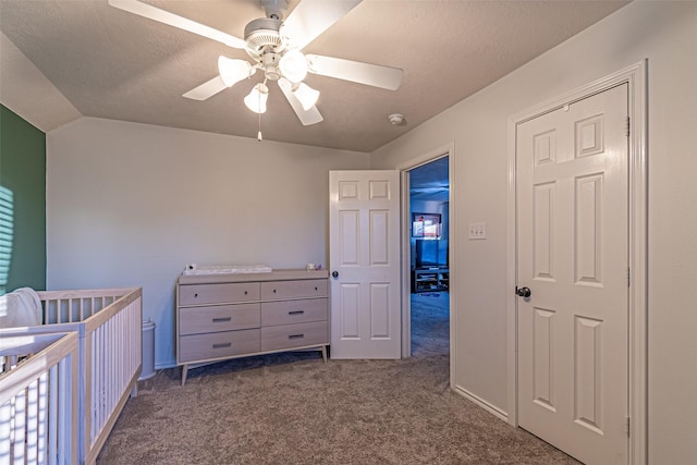 carpeted bedroom featuring ceiling fan, a nursery area, a textured ceiling, and lofted ceiling