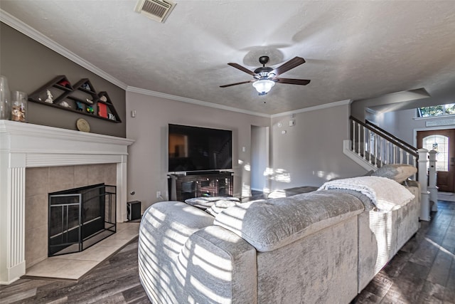 living room with a textured ceiling, wood-type flooring, crown molding, and a fireplace