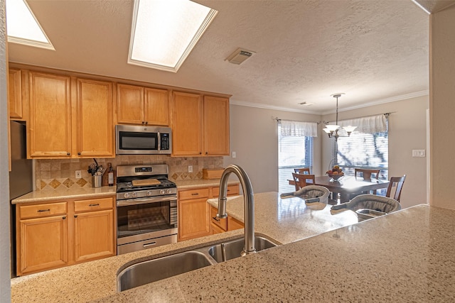 kitchen featuring sink, ornamental molding, appliances with stainless steel finishes, and pendant lighting