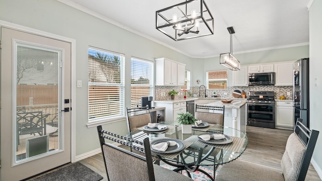 dining room featuring sink, crown molding, light hardwood / wood-style floors, and a chandelier