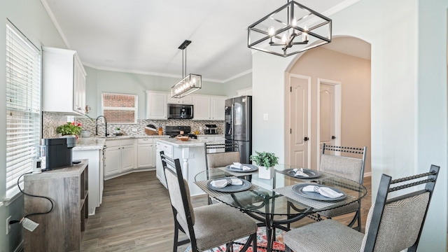 dining room with light hardwood / wood-style flooring, sink, crown molding, and a wealth of natural light