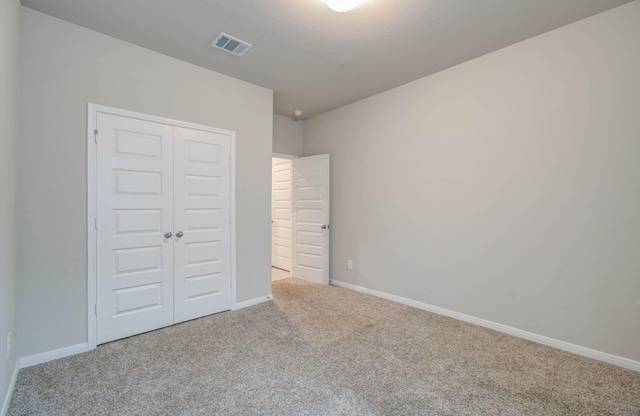 unfurnished bedroom with a closet and light carpet