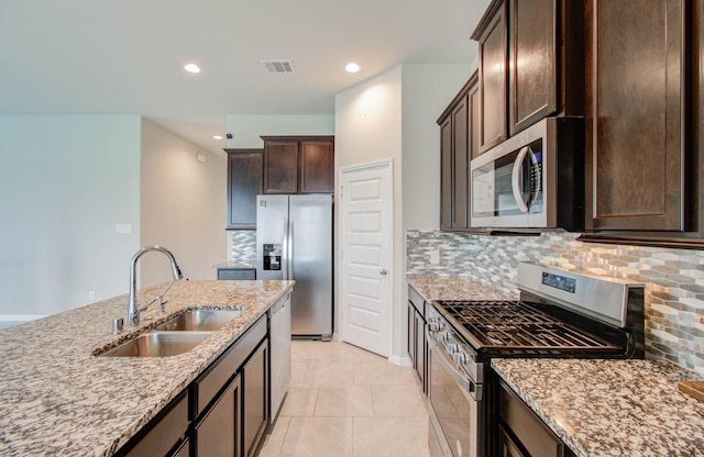 kitchen with decorative backsplash, sink, light stone countertops, appliances with stainless steel finishes, and light tile patterned floors