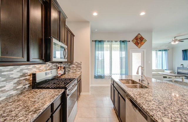 kitchen with sink, plenty of natural light, stainless steel appliances, light tile patterned floors, and light stone counters