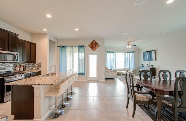 kitchen featuring backsplash, sink, a kitchen island with sink, stainless steel appliances, and dark brown cabinets