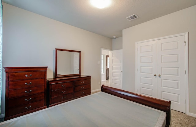 bedroom featuring a textured ceiling, a closet, and light carpet