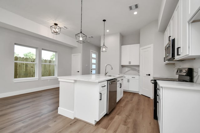 kitchen featuring pendant lighting, light hardwood / wood-style flooring, appliances with stainless steel finishes, an island with sink, and white cabinets