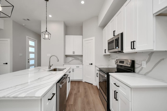 kitchen with pendant lighting, white cabinetry, stainless steel appliances, sink, and backsplash