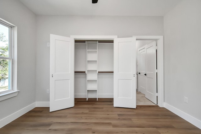 unfurnished bedroom with ceiling fan, hardwood / wood-style flooring, and multiple windows