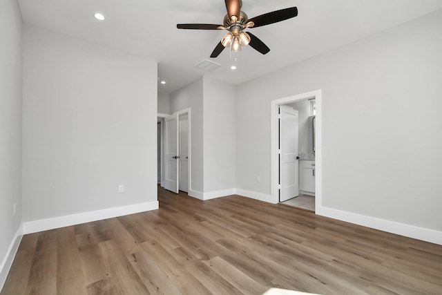 unfurnished bedroom featuring ensuite bathroom, ceiling fan, and light wood-type flooring