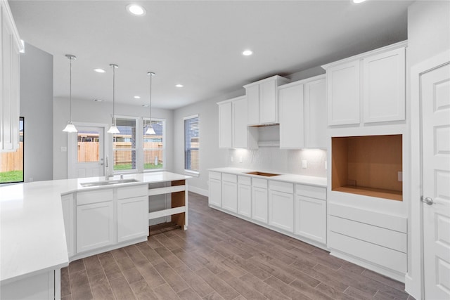 kitchen featuring recessed lighting, a sink, white cabinetry, decorative backsplash, and wood finished floors