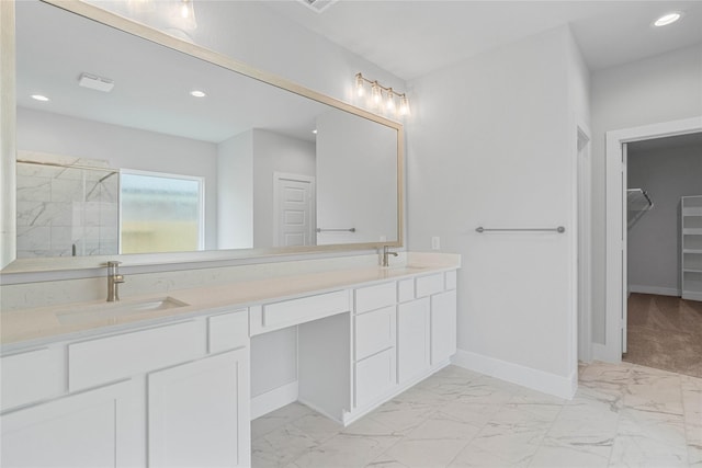 bathroom featuring a sink, marble finish floor, a spacious closet, double vanity, and baseboards