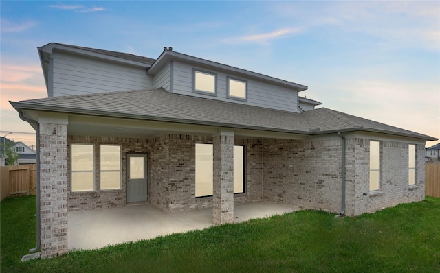 rear view of property featuring a patio area, a shingled roof, and fence