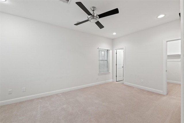 unfurnished bedroom featuring ceiling fan, a spacious closet, light carpet, and a closet