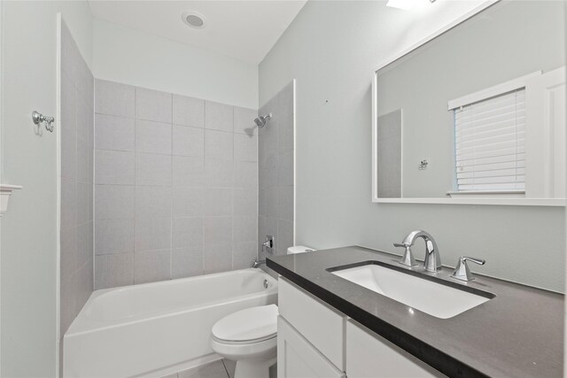 full bathroom featuring tiled shower / bath, vanity, toilet, and tile patterned floors