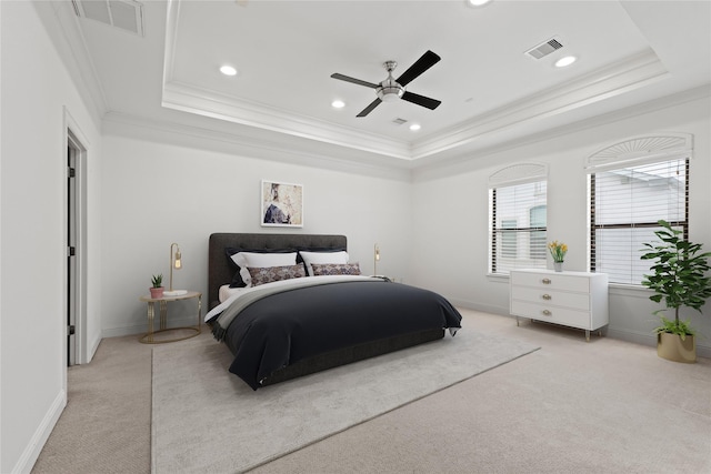 bedroom with crown molding, light colored carpet, ceiling fan, and a tray ceiling