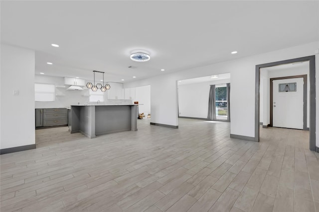 kitchen featuring hanging light fixtures, light wood-type flooring, gray cabinets, and a kitchen island