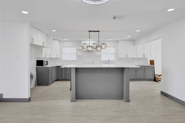 kitchen featuring decorative light fixtures, a center island, and gray cabinetry