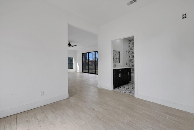 spare room with sink, ceiling fan, and light wood-type flooring