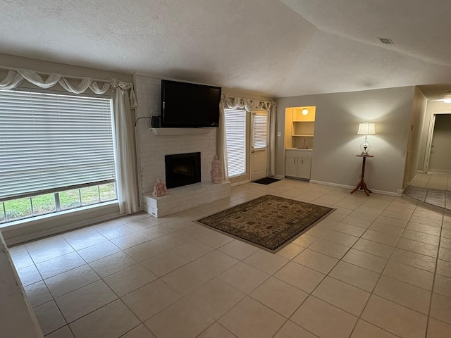 unfurnished living room with vaulted ceiling, light tile patterned floors, a textured ceiling, and a fireplace