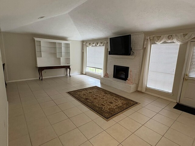 unfurnished living room featuring lofted ceiling, a fireplace, light tile patterned flooring, and a textured ceiling