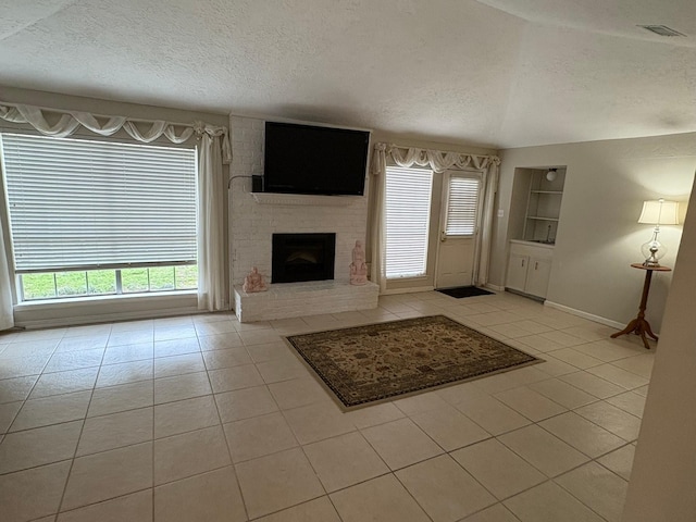 unfurnished living room with built in shelves, a brick fireplace, light tile patterned flooring, and a textured ceiling