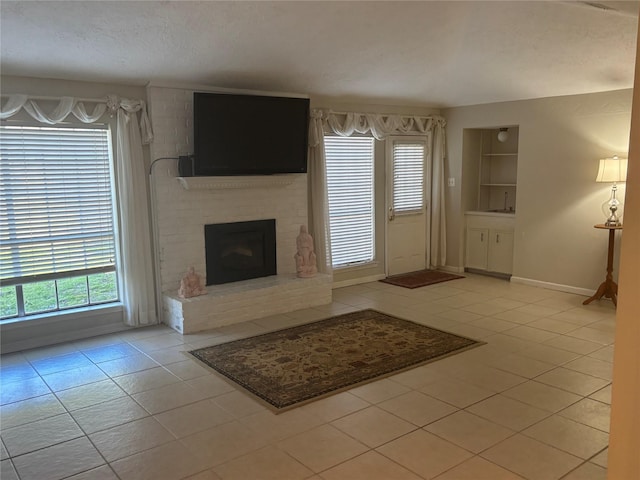 unfurnished living room with a fireplace, baseboards, a textured ceiling, and light tile patterned flooring