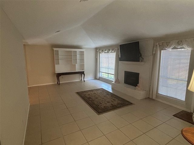 unfurnished living room featuring tile patterned flooring, a large fireplace, vaulted ceiling, and baseboards