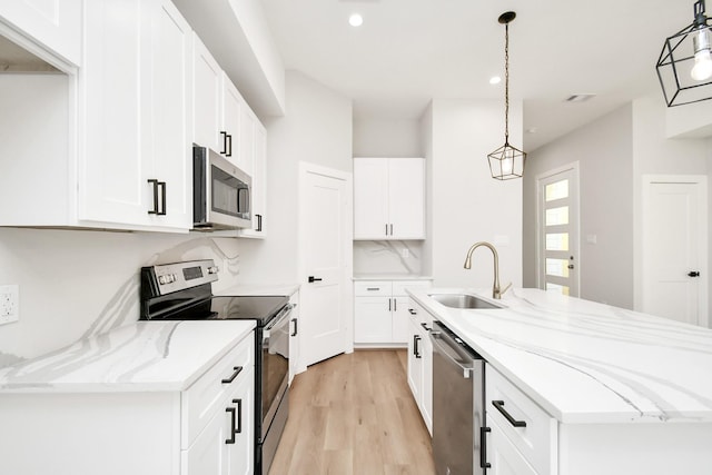 kitchen featuring hanging light fixtures, appliances with stainless steel finishes, an island with sink, and white cabinetry